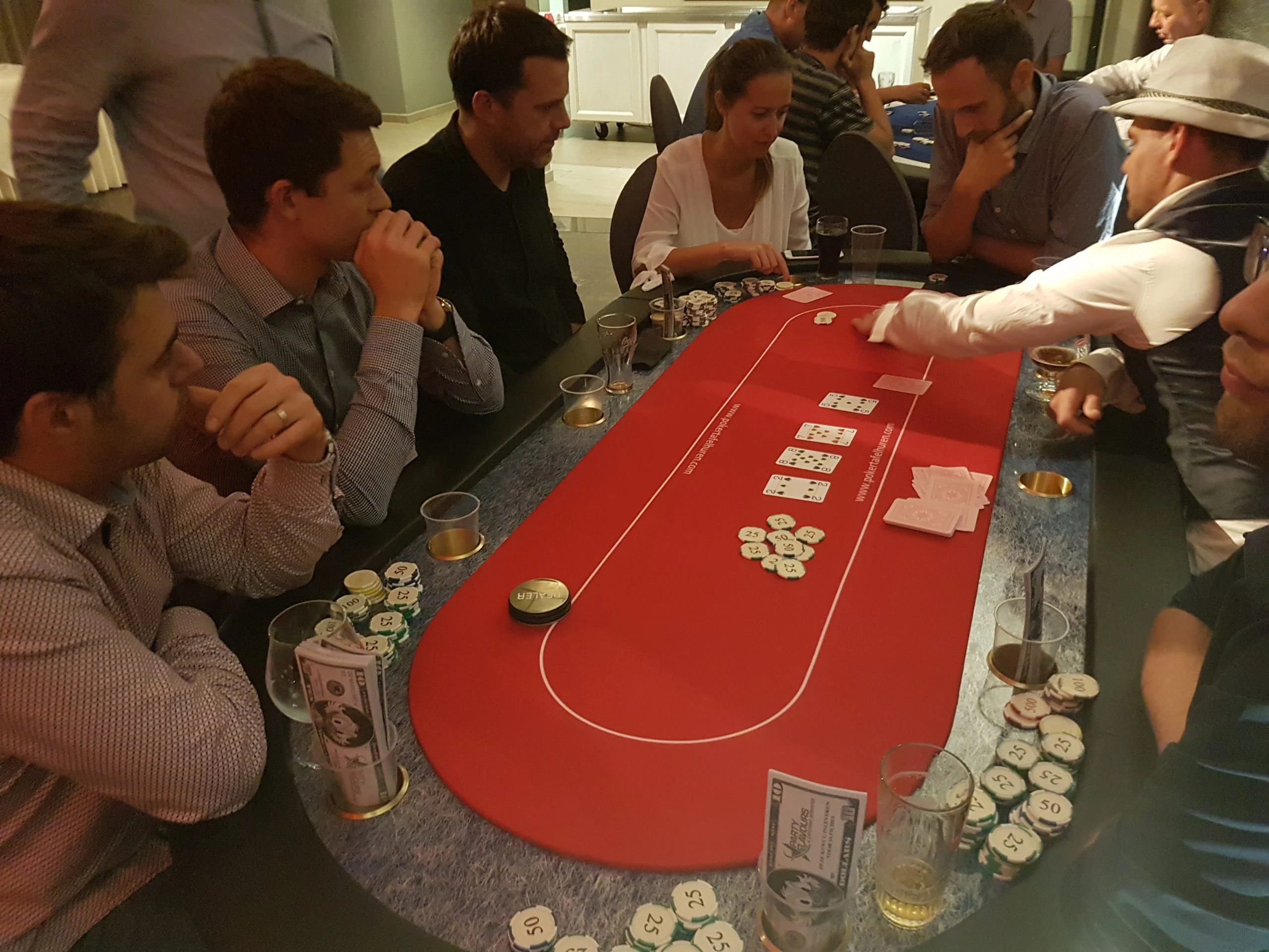 Gasten en croupier rond de pokertafel tijdens het event