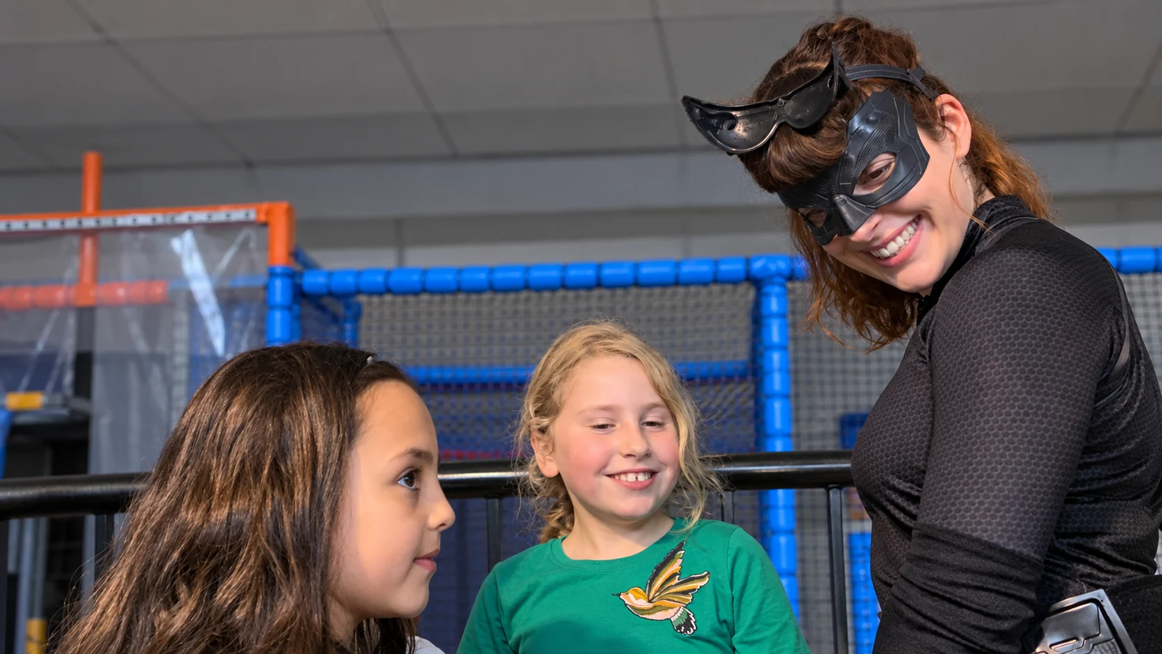 Catwoman lacht samen met twee kinderen in de speeltuin
