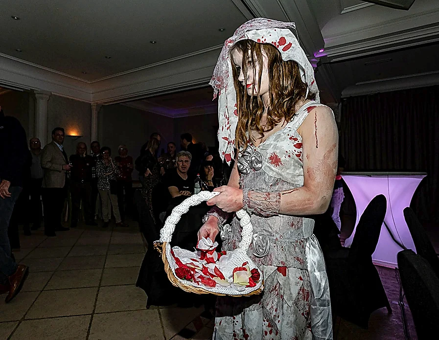 Halloweenperformer in bruidskostuum met bloemenmand