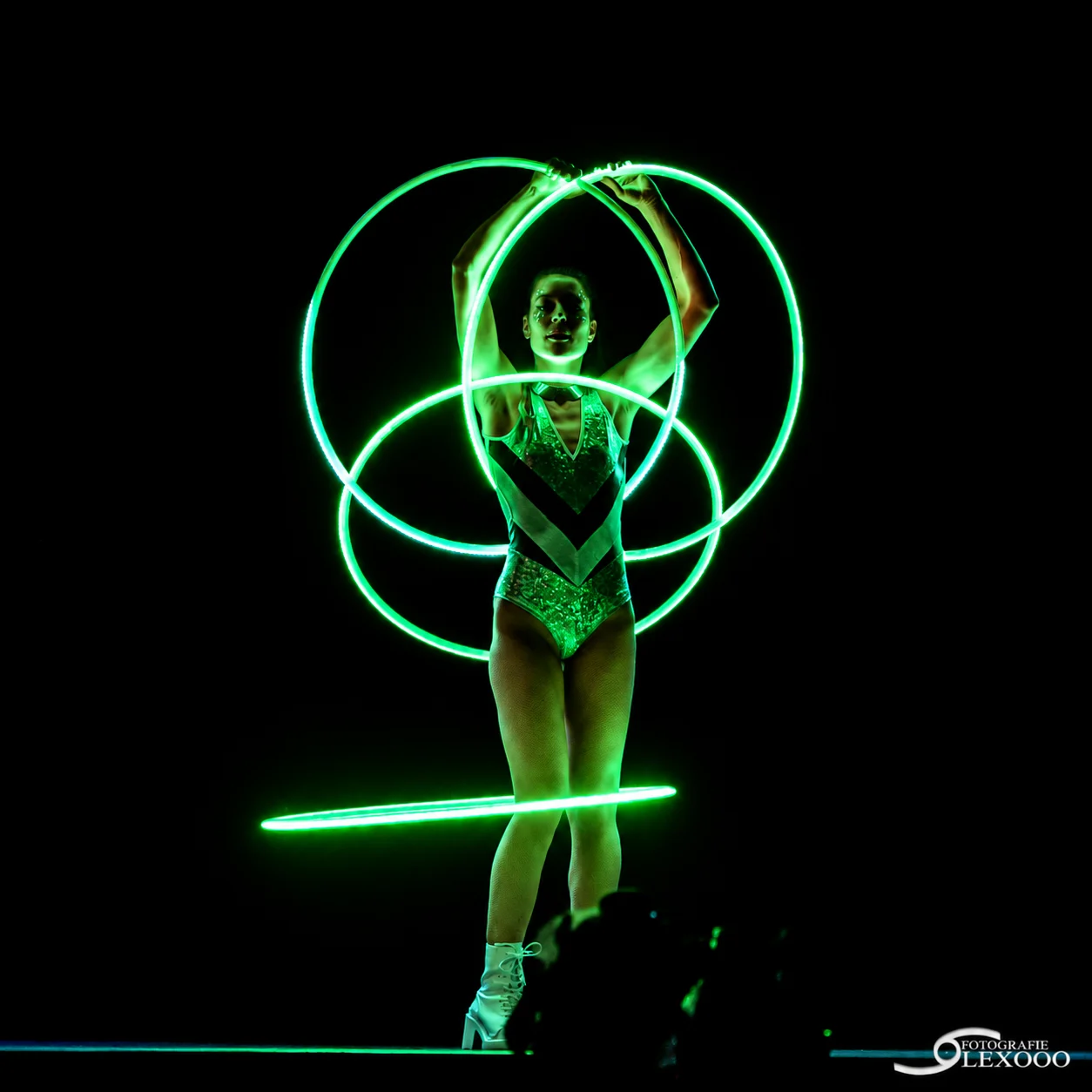 Performer met groene LED-hoepels tijdens het echte lichtfestival