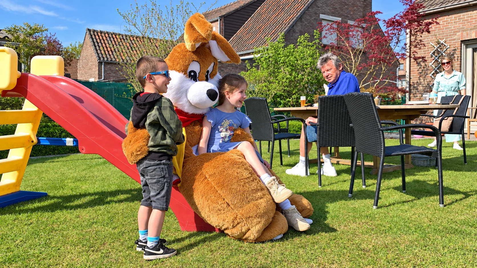 Kinderen bij de Paashaas op de glijbaan in een echte tuinsetting